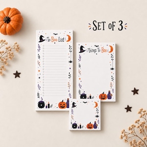 May include: A set of three white paper notepads featuring Halloween-themed illustrations of pumpkins, witch hats, moons, and cauldrons. The tall notepad reads To Boo List, the medium notepad reads Things To Boo, and the small square notepad is blank.
