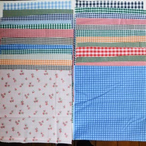 May include: A collection of fabric swatches in various colors and patterns. The swatches include gingham, floral, and solid designs in shades of blue, red, black, green, and orange. The fabrics are arranged in a neat, organized display.