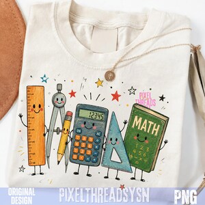 May include: A cream-coloured t-shirt featuring a graphic print of anthropomorphic school supplies including an orange ruler, a compass, a yellow pencil, a blue calculator, a blue triangle, and a green book with the text MATH and numbers.