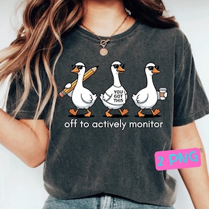 Pode incluir: T-shirt cinzento escuro com um desenho de três gansos de desenho animado a usar óculos de sol. Um ganso segura um lápis, outro tem uma camisola que diz "YOU GOT THIS" e o terceiro carrega uma chávena de café. O texto "off to actively monitor" está por baixo.