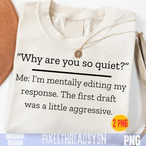May include: A cream-colored t-shirt featuring black text that reads: Why are you so quiet? Me: I'm mentally editing my response. The first draft was a little aggressive. A thin gold chain necklace with a small circular pendant rests on the neckline.
