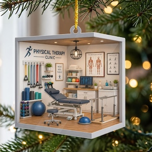 May include: A square-shaped hanging ornament depicting a miniature physical therapy clinic. The interior features a treatment table, a rolling stool, parallel bars, resistance bands, dumbbells, a yoga ball, and anatomical wall charts.
