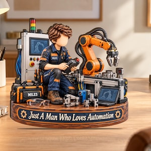 May include: A figurine of a technician in a blue uniform with the name Miles, operating a robotic arm. The base features the text Just A Man Who Loves Automation, a control panel, a laptop, a tool bag, and safety glasses on a wooden surface.
