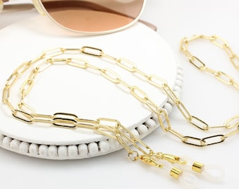 May include: Gold chain eyeglasses holder with clear silicone ends. The chain is made of linked oval shapes.