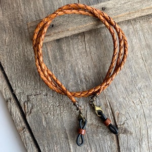 May include: A brown leather braided glasses chain with black metal and rubber ends.