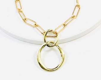May include: A gold chain necklace with a large, textured, gold circle pendant.