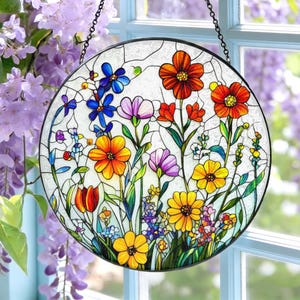 Könnte beinhalten: Ein rundes Buntglasfenster mit einem farbenfrohen Blumendesign. Die Blumen umfassen orange, gelbe, blaue und lila Blüten mit grünen Stielen und Blättern. Das Panel ist schwarz umrandet und hängt an einer Kette.