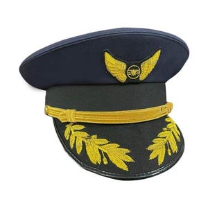 May include: A navy blue pilot's hat with gold embroidered wings and a circular emblem. The hat features a black band with gold trim and embroidered gold leaves on the brim. A classic aviation accessory.