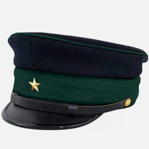 May include: A navy blue and forest green military-style hat with a black brim. The hat features a gold star emblem and a black leather strap. A gold button is on the side of the hat.