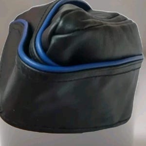 May include: Black leather hat with a blue trim. The hat has a rounded top and a brim that curves up. The blue trim outlines the hat's edges, adding a pop of color to the otherwise dark design. The hat appears to be made of a soft, pliable leather.