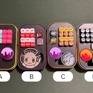 May include: Four small, rectangular metal cases, each containing dice and game tokens. The cases are labelled A, B, C, and D. Each case has a different arrangement of dice, including six-sided dice and dice with numbers like 20 and 100.