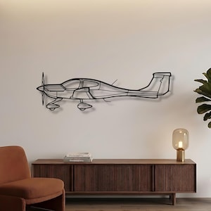 Könnte beinhalten: Schwarze Metall-Wandkunst eines Flugzeugs. Das Kunstwerk zeigt eine detaillierte Umrisszeichnung eines kleinen Flugzeugs mit Propeller, Flügeln und Leitwerk. Das Kunstwerk ist an einer weißen Wand angebracht und verleiht der Raumdekoration eine moderne Note.