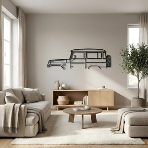 Op de afbeelding: Zwart metalen wandkunstwerk dat een zijaanzicht van een vintage SUV afbeeldt. Het kunstwerk is gemonteerd op een neutraal gekleurde muur in een woonkamer, met een bank, salontafel en andere decoraties.