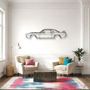 May include: A black metal car outline wall art decor. The artwork depicts a classic car profile, mounted on a white wall. The room features two armchairs, a trunk, a floor lamp, and a colorful rug.