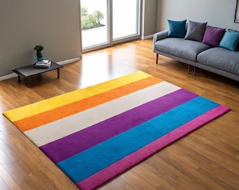 May include: A rectangular area rug with horizontal stripes in yellow, orange, white, purple, blue, and pink. The rug is placed on a hardwood floor in a living room setting. The rug's design adds a vibrant pop of color to the room's decor.