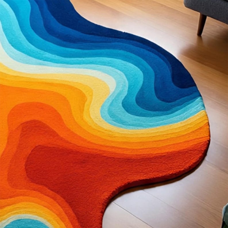 May include: A colorful, abstract rug with a wave-like design. The rug features a gradient of colors, transitioning from deep red to orange, yellow, light blue, and finally, dark blue. The rug's shape is organic and irregular, adding to its unique aesthetic.
