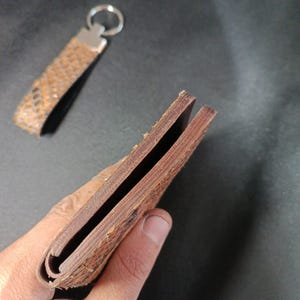 wallet with an exotic embossed finish and matching leather keychain accessory."