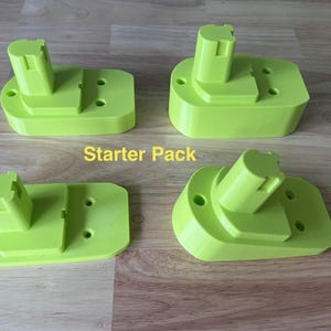May include: Four lime green battery holders on a wooden surface. Each has a rectangular base, a raised platform, and a cylindrical connector. The text "Starter Pack" is visible.