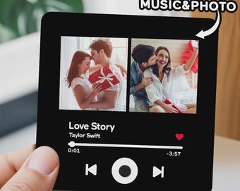 May include: Black square with two photos of a couple, resembling a music player interface. The text "Love Story" by Taylor Swift is displayed, along with playback controls and the words "CUSTOM MUSIC & PHOTO". A hand holds the square.