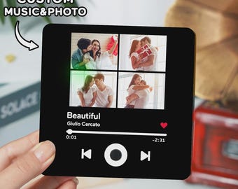 May include: A black square with a music player interface design. The text "CUSTOM MUSIC & PHOTO" is at the top. Four photos are displayed above the song title "Beautiful" by Giulio Cercato. A hand holds the square.