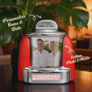 Peut inclure: Un cadre photo de style rétro rouge et argenté avec une photo d'un couple. Le cadre porte les inscriptions "Personnaliser Nom et Date" et "Photo et Musique personnalisées". Le haut du cadre porte les inscriptions "William & Jane" et la date "09-24-2025".