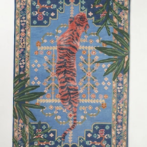 May include: Rectangular blue rug with a central design of a standing tiger with orange and black stripes. The rug has a detailed border with floral and geometric patterns, and green palm fronds frame the tiger.