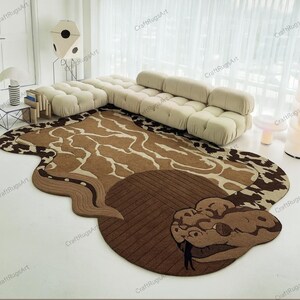 Op de afbeelding: Een bruin en tan tapijt in de vorm van een slang, met een gedetailleerd hoofd en lichaamsmotief. Het tapijt heeft een textuurontwerp en ligt op een witte vloer. Het tapijt staat in de buurt van een beige bank.