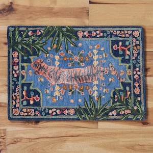 May include: Rectangular rug with a blue background and a tiger design. The tiger is orange with black stripes. The rug has a dark blue border with floral and leaf accents. The rug is placed on a wooden floor.