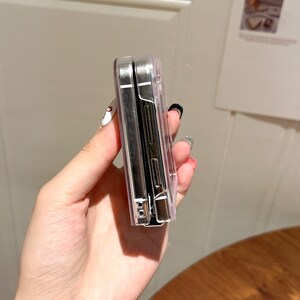 May include: Clear phone case with a silver frame. The case is made of transparent plastic and has a sleek, modern design. The phone case is designed to protect the phone from scratches and other damage.