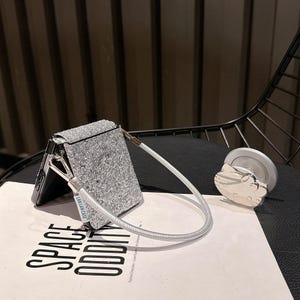 May include: A set of three ceramic mugs with a speckled, matte finish. The mugs are in shades of cream, light gray, and dark gray. Each mug has a simple, minimalist design, perfect for coffee or tea.