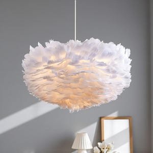 May include: A white, feather pendant light. The light fitting is round, resembling a cloud due to the many white feathers. It hangs from a white cord and provides a soft, ambient glow to the room.