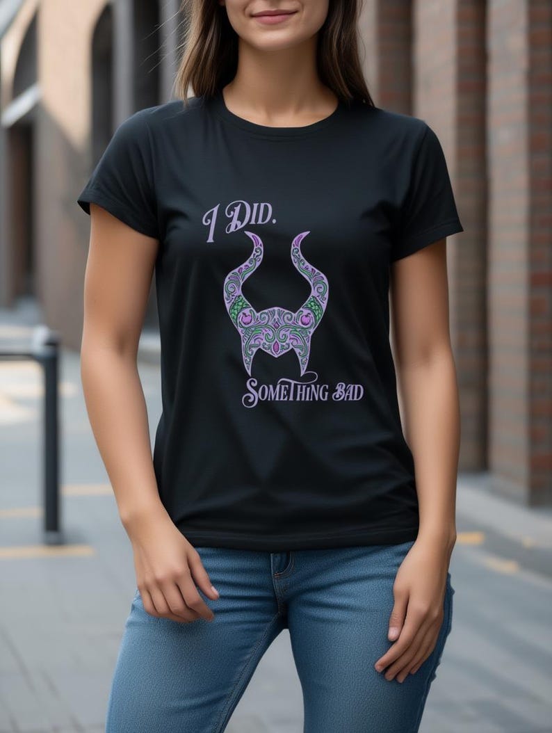 May include: Black t-shirt featuring the text "I Did. Something Bad" in a stylized font. The shirt design includes a purple and green horned silhouette. The shirt is paired with blue jeans.