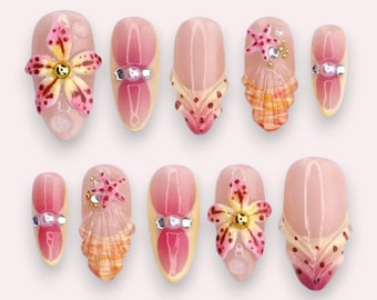Luxe roze persnagels met 3D tropische bloemen, schelpen en sprankelende kristallen.