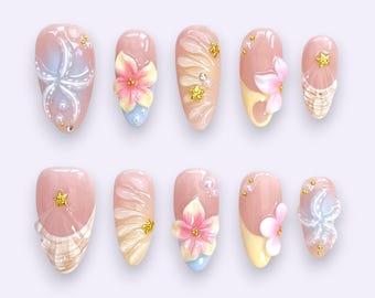 Tropische Blütenpresse auf Nägeln mit Muscheldetails und Pastellsonnenuntergangakzenten