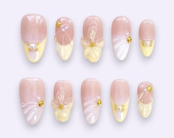 Zachtgele madeliefjespers op nagels met parelgouden bedelaccenten