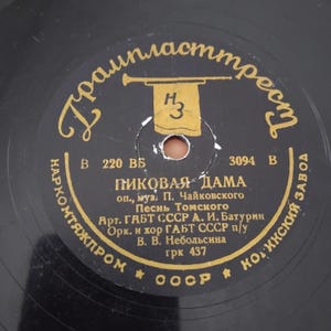 Pode incluir: Um disco de vinil preto com letras douradas e um rótulo central. O rótulo apresenta texto cirílico, um emblema de trompete e o título "Pikovaia Dama". O disco é da URSS.