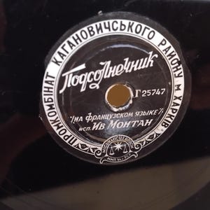 Pode incluir: Um rótulo de disco de vinil preto com texto branco e um orifício central. O rótulo apresenta texto cirílico, incluindo "Подсолнечник" e "ИВ Монтан". O rótulo também inclui o texto "НА ФРАНЦУЗСКОМ ЯЗЫКЕ".
