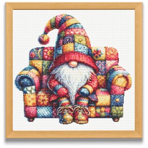 Può includere: Un punto croce incorniciato di una figura di gnomo seduta su una poltrona patchwork. Lo gnomo indossa un cappello alto e colorato e un abito rosso. La poltrona e i vestiti dello gnomo presentano una varietà di quadrati a motivi nei toni del rosso, blu, giallo e verde.