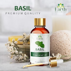 Può includere: Un flacone in vetro marrone di olio essenziale di basilico Earth Nourish Premium Quality con tappo dorato e contagocce in vetro separato. L'etichetta bianca presenta un grafico con foglia di basilico verde e il testo 30ml.