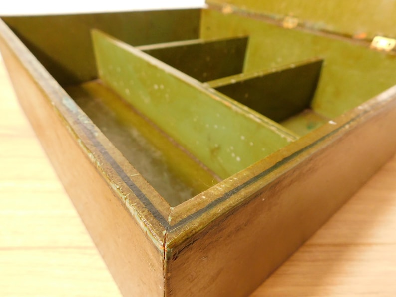 May include: An open, antique wooden box with a brown exterior and a green interior. The box is divided into several compartments. The edges of the box are lined with a dark trim.