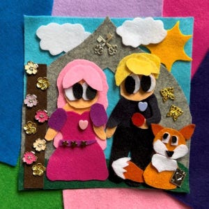 May include: A felt art piece featuring a couple and a fox in front of a gray building with golden keys. The woman wears a pink dress and the man wears a black suit. A yellow sun and white clouds are in the blue sky.