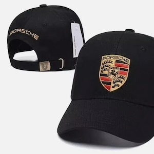 May include: Black baseball cap featuring the Porsche logo on the front and the word "PORSCHE" embroidered in gold on the back. The cap has a curved brim and an adjustable strap.
