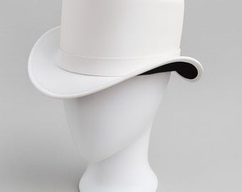 May include: A white top hat with a wide brim and a band around the crown. The hat is displayed on a white mannequin head against a grey background. The hat's interior is black.