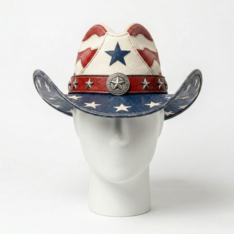 Op de afbeelding: Een patriottische cowboyhoed met een witte kroon met rode strepen en een grote blauwe ster. De rand is blauw met witte sterren. Een rode band met zilveren sterren en een centraal embleem omcirkelt de hoed.