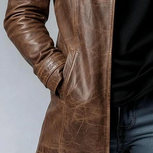 May include: A brown leather jacket with a classic design. The jacket features a notched collar, a button-down front, and multiple pockets. The leather has a distressed look, adding to its vintage appeal.