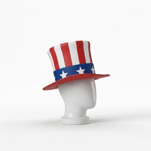 May include: A red, white, and blue Uncle Sam hat with a blue band featuring white stars. The hat is displayed on a white mannequin head, perfect for patriotic events and celebrations.