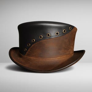 May include: A two-tone top hat with a black leather upper section and a brown leather lower section. The hat features a curved design and is adorned with gold-colored eyelets along the seam. The brim is also brown leather.