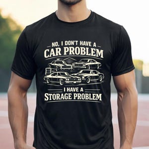 May include: Black t-shirt with a white graphic of classic cars and the text "NO, I DON'T HAVE A CAR PROBLEM I HAVE A STORAGE PROBLEM". The design features four vintage cars and a garage.