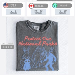 May include: A dark gray t-shirt with the text "Protect Our National Parks" in pink. Below the text are blue illustrations of forest creatures. The shirt is labeled "pepper" in the image.