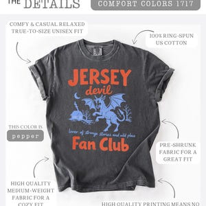 May include: Pepper-colored t-shirt with the text "Jersey Devil Fan Club" in orange. The design features a blue illustration of the Jersey Devil creature with a moon and trees. Made of 100% ring-spun US cotton, pre-shrunk for a great fit.